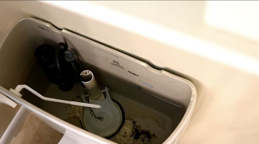 Open toilet tank showing a new flapper and flush valve chain
