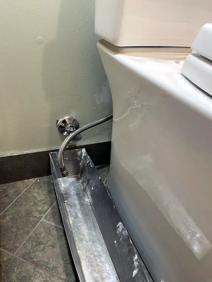 Toilet supply line and shutoff valve at the wall behind a toilet