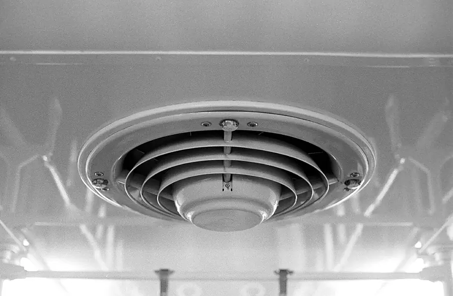 Round metal ventilation fan grille set into a white bathroom ceiling