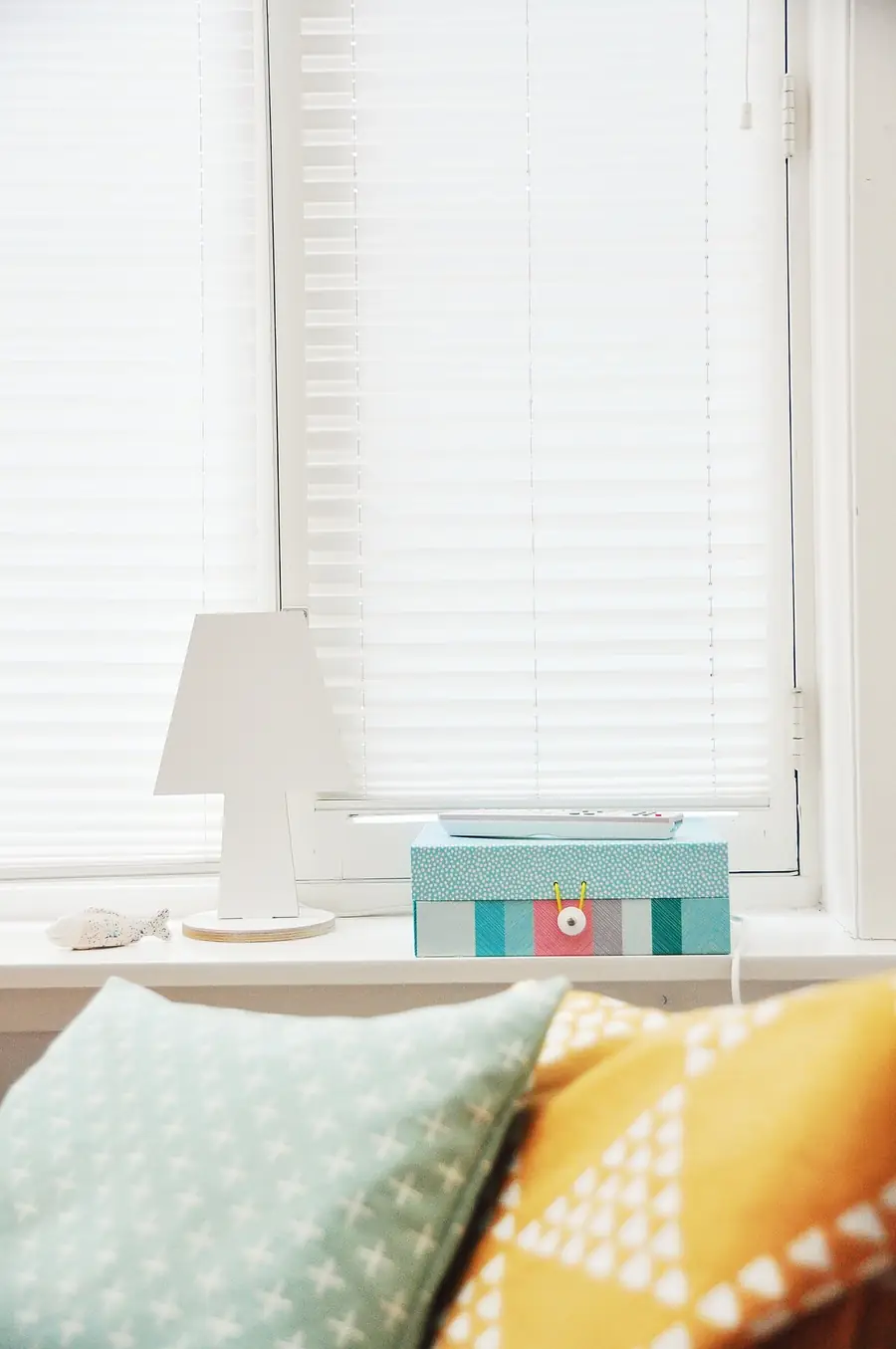 Window with a sheer curtain and blinds over a bed