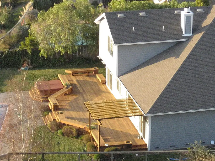 Raised backyard wood deck with railings and steps behind a two-story house