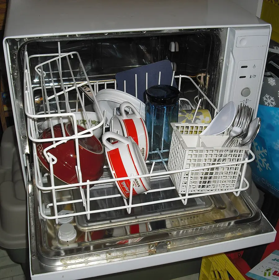 打开的洗碗机，拉出的碗篮里放着碗碟和餐具