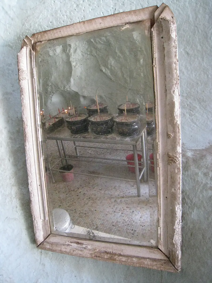 Rectangular mirror in a pale distressed wood frame hung on a wall
