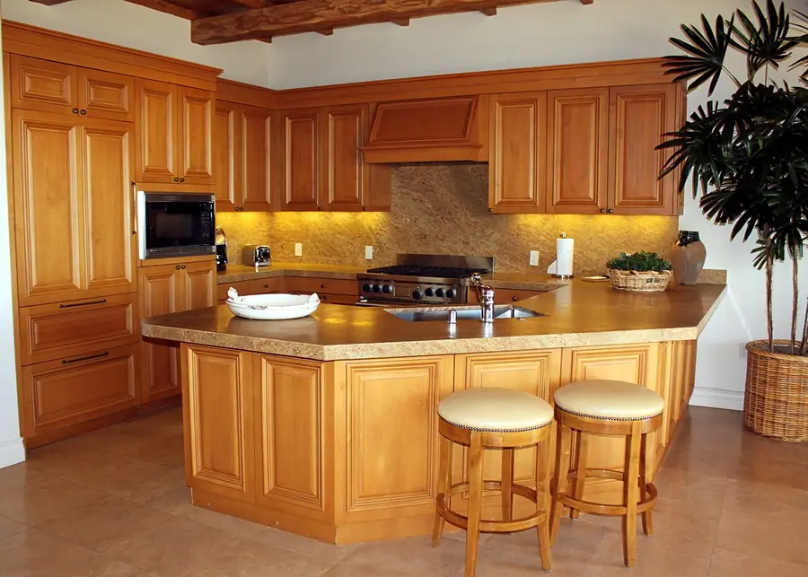 Kitchen with wood cabinets, a stainless range hood and an island with stools