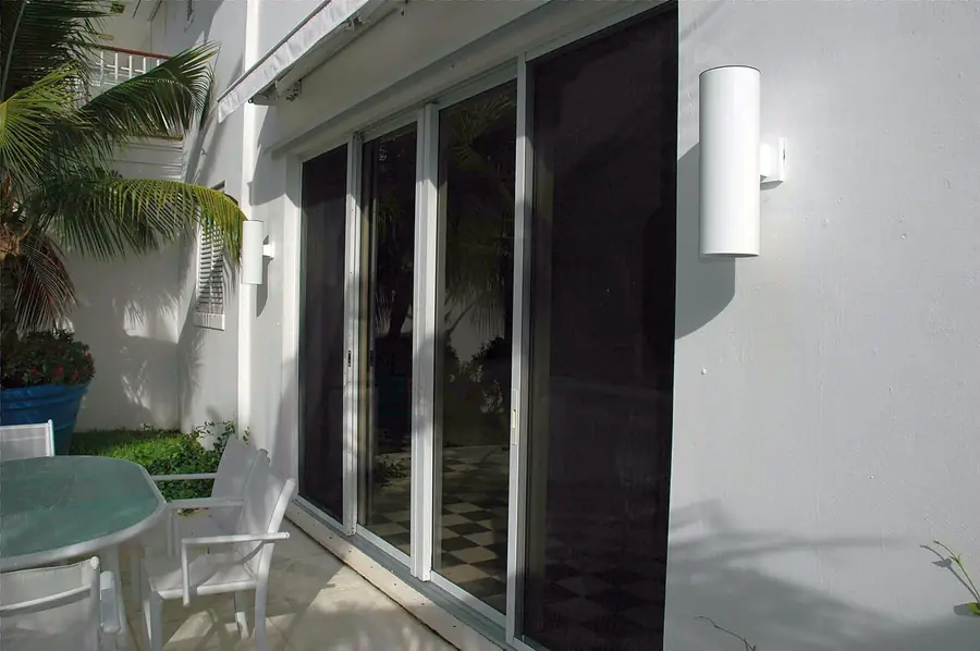Modern patio with tall sliding glass doors opening from a white house