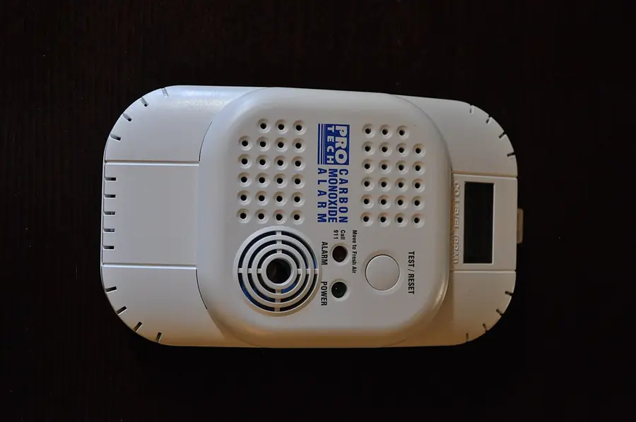 White plug-in carbon monoxide alarm with a digital display on a dark background