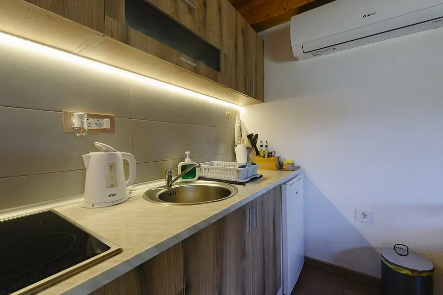 Kitchen counter and sink lit by a light strip under wood cabinets