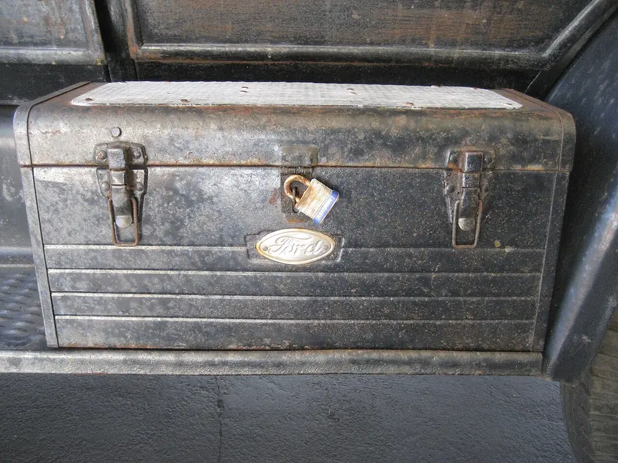 Old gray metal toolbox with a latch and handle sitting on a shelf