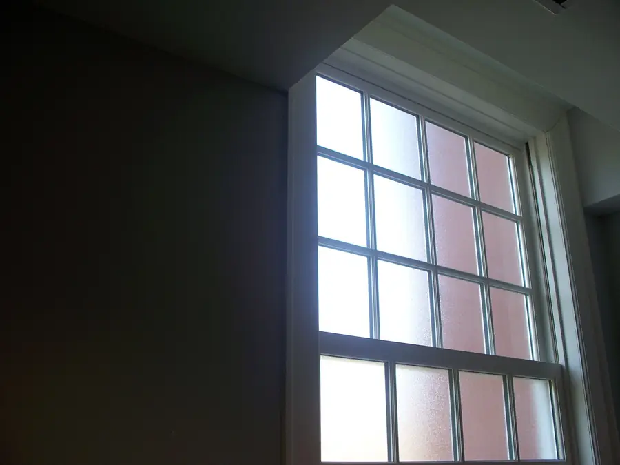 Tall multi-pane window with frosted glass seen from inside a dark room
