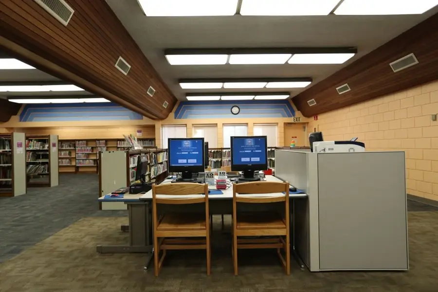 Inside the Duarte Library with bookshelves, tables and public computers