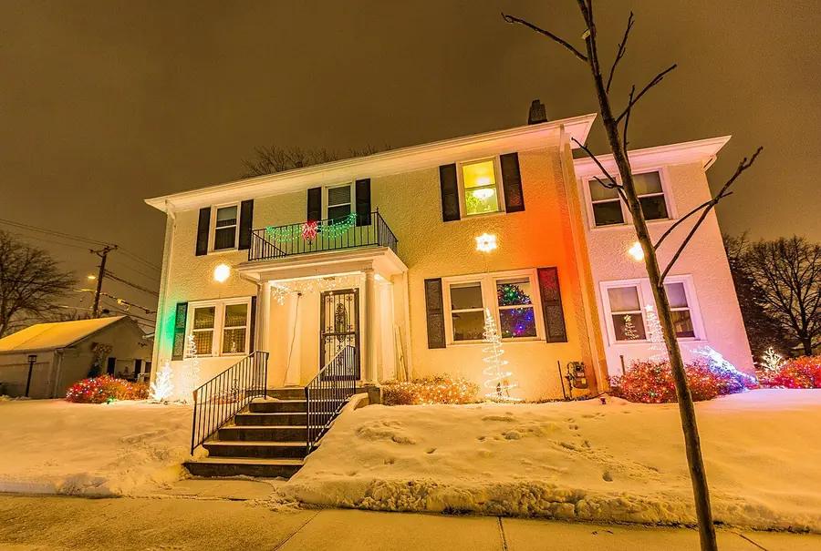 House at night with holiday lights along the porch and roofline