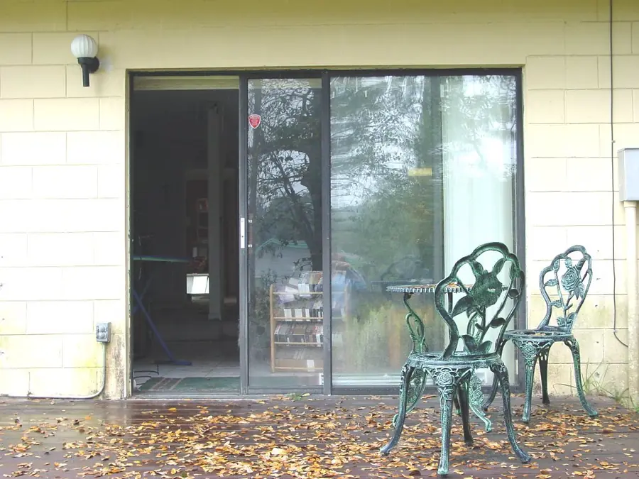Sliding glass door with metal patio chairs outside a building