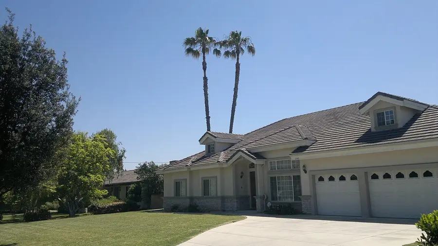 Single-story stucco house with a wide driveway and palm trees in Arcadia