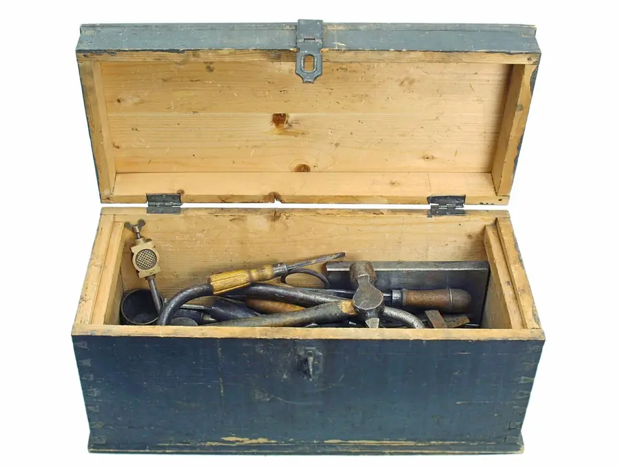 Old wooden tool chest opened to show wrenches and hand tools