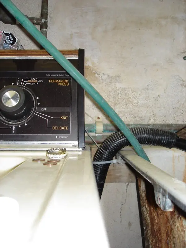 Washing machine drain hose and water line behind an older top loader
