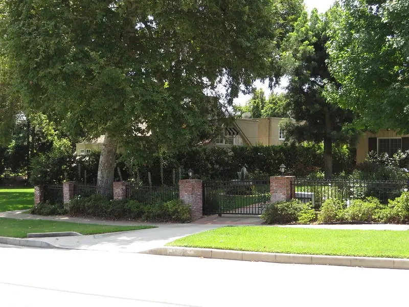 Brick gate posts, green lawn and big shade trees on a San Marino street