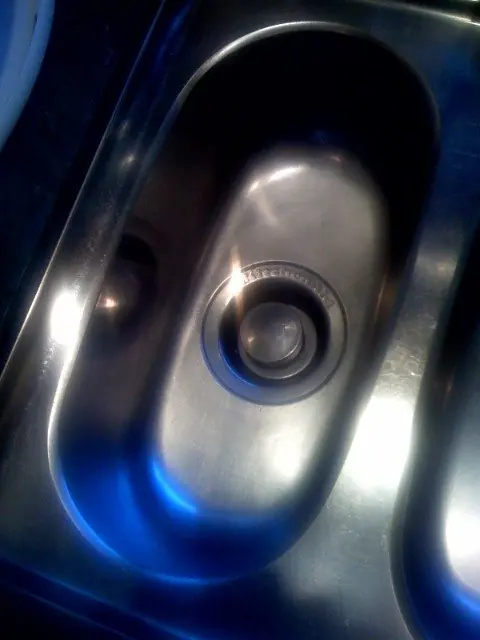 Stainless steel kitchen sink basin with the drain opening for a disposal