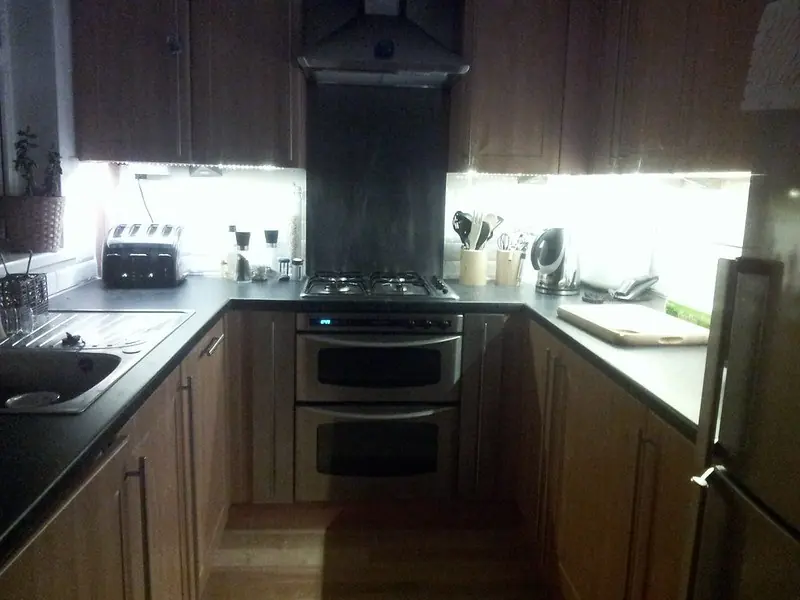 Bright lights under kitchen wall cabinets shining on a dark countertop