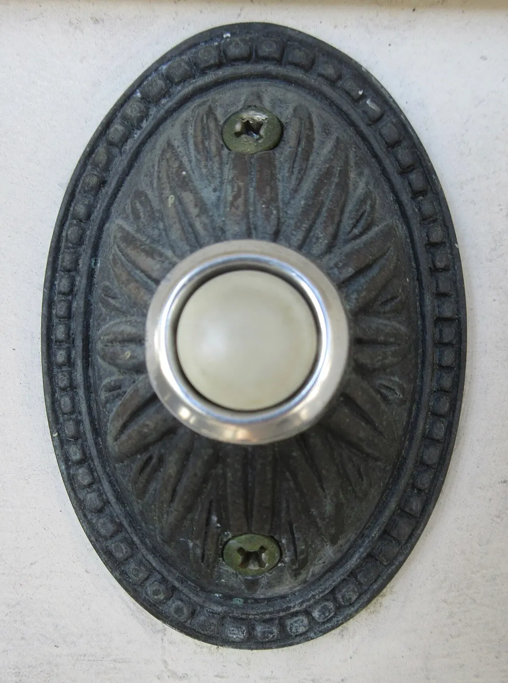 Round doorbell button mounted beside a front door
