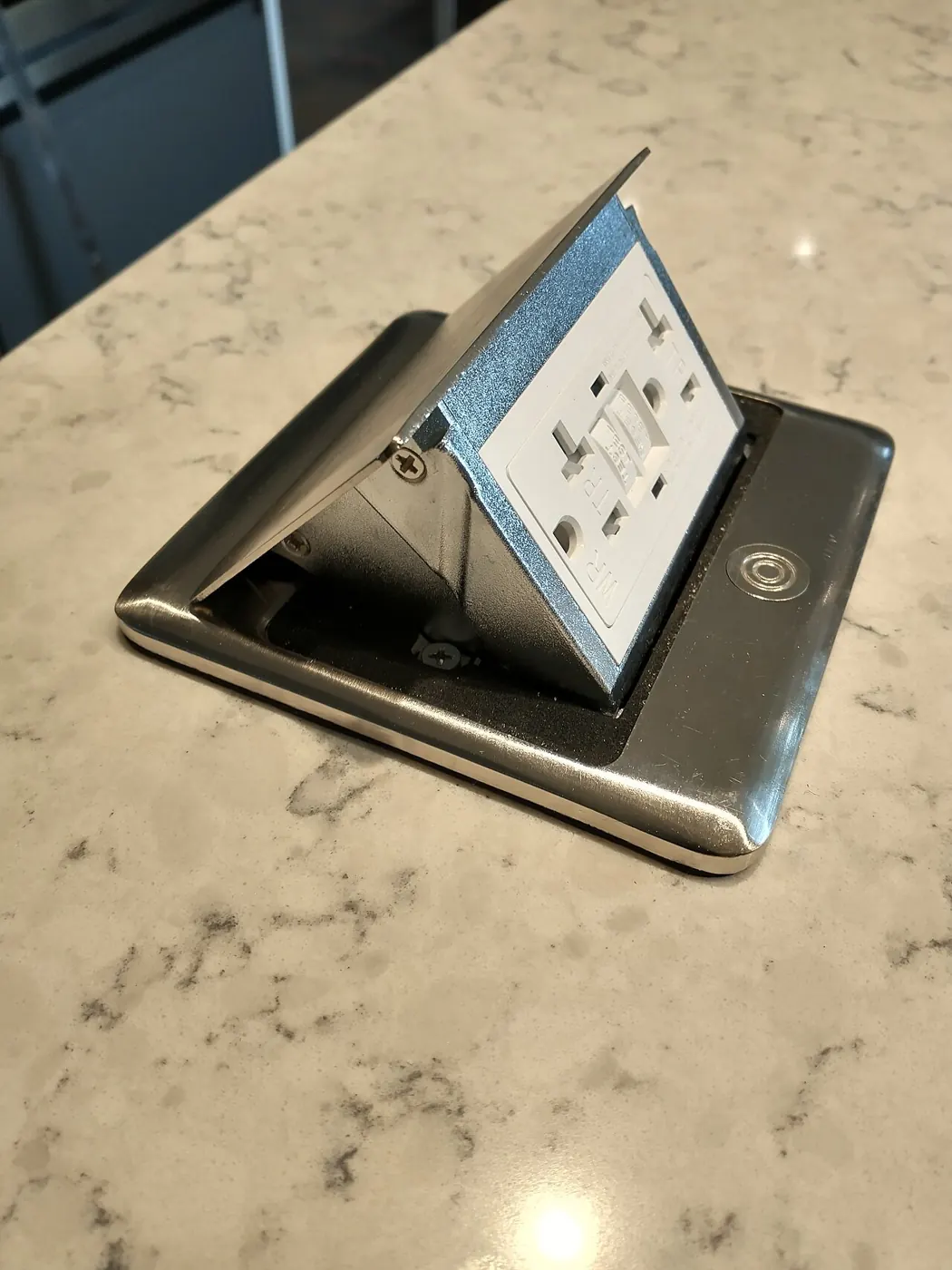 Pop-up power outlet set into a countertop