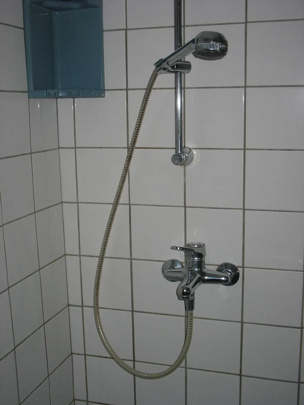 Single-handle shower valve and hand shower on a tiled wall