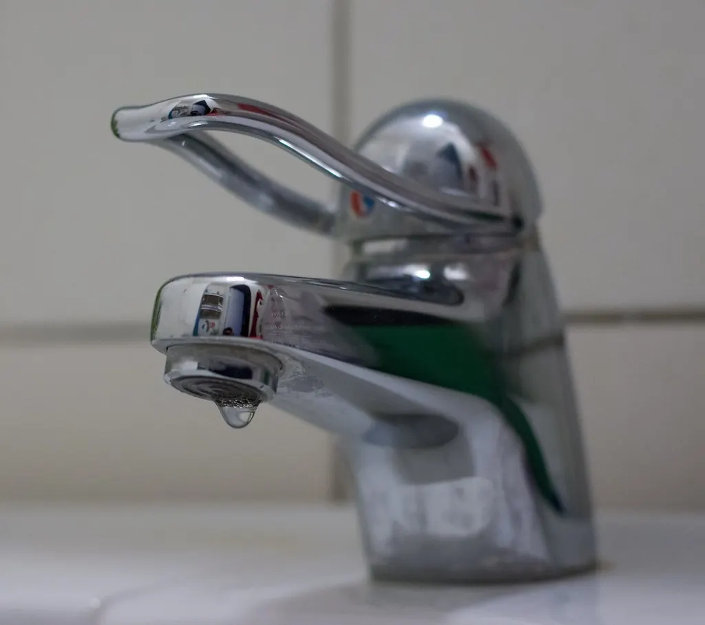Chrome bathroom faucet with a drip at the spout
