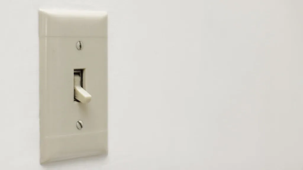 Cream toggle light switch on a white wall