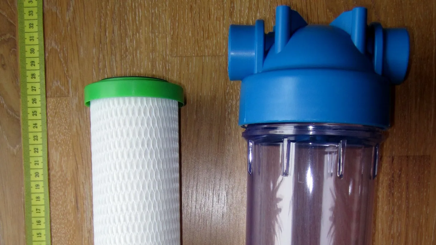 A white carbon filter cartridge beside a clear filter housing with a blue cap