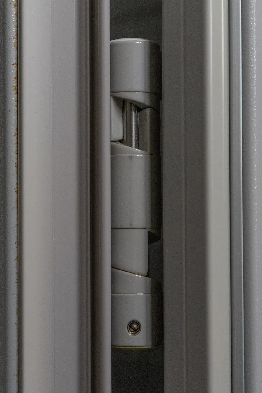 Close view of a spring hinge mounted on a gray metal door frame