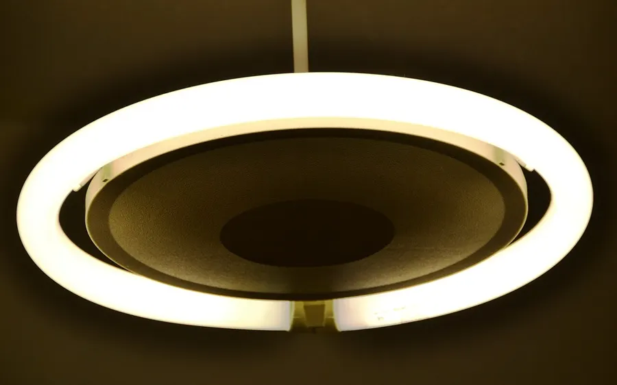 Glowing ring-shaped LED ceiling light fixture seen from below in a dark room