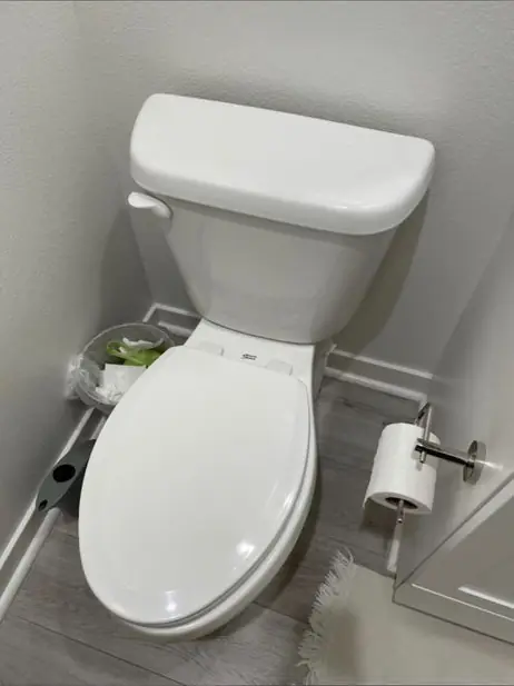 White elongated toilet installed next to a vanity on a gray tile floor