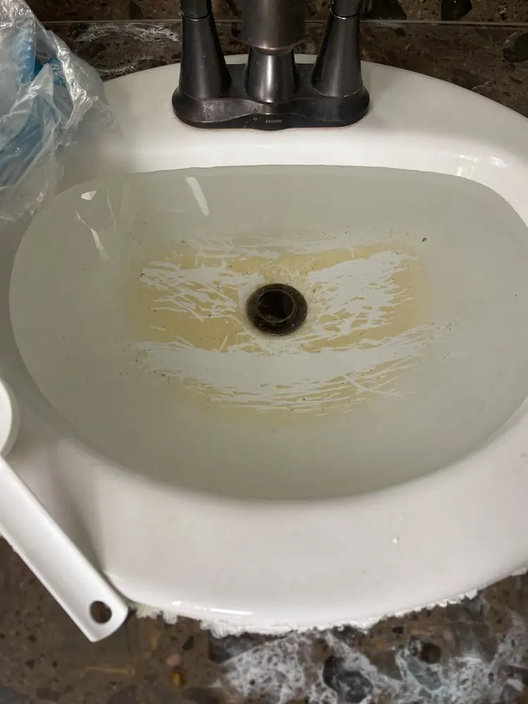 Close photo of a stained bathroom sink bowl and drain opening