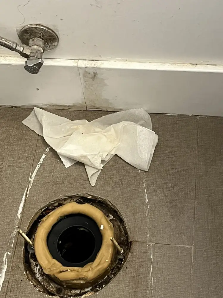 Toilet flange and fresh wax ring on a bathroom floor before the toilet is reset