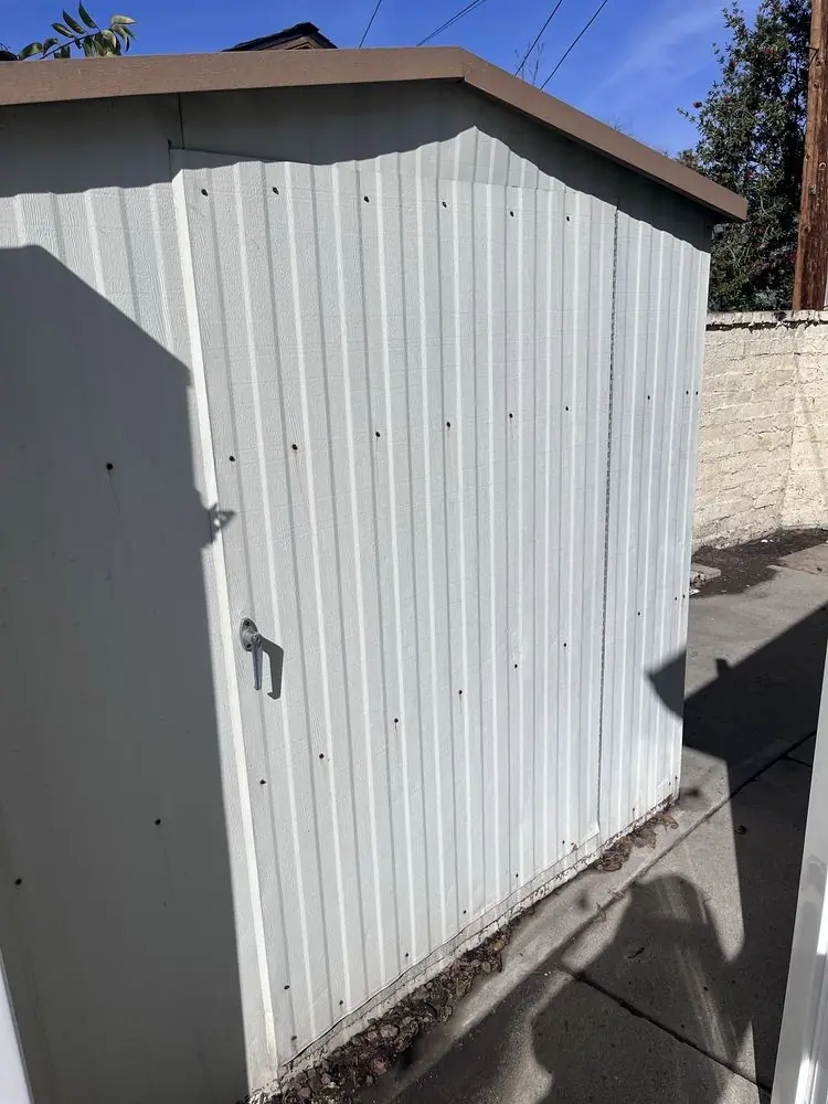 Assembled metal storage shed standing in a side yard
