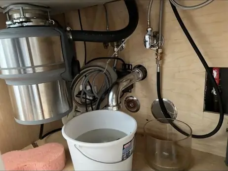 水槽下新换的厨余机，下方放着水桶
