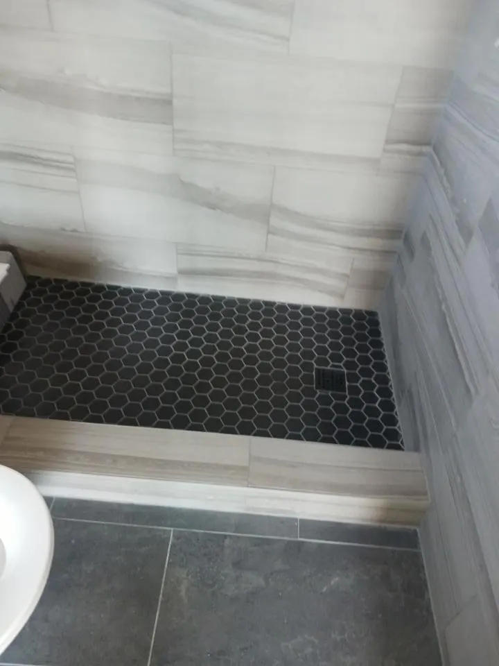 Shower floor of small black hexagon tile with gray grout lines