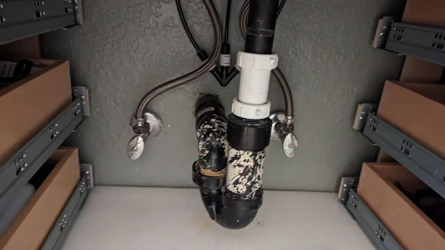 Sink drain and P-trap under a bathroom vanity, with supply lines on each side